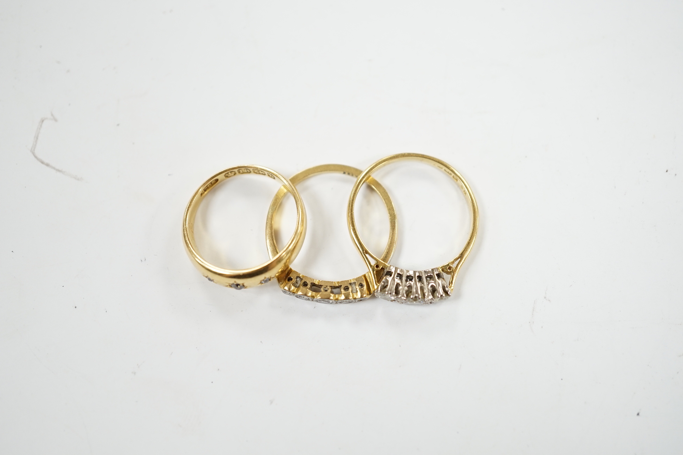 A late Victorian 18ct gold and gypsy set three stone diamond chip ring and two other 18ct and diamond set rings, three stone and five stone